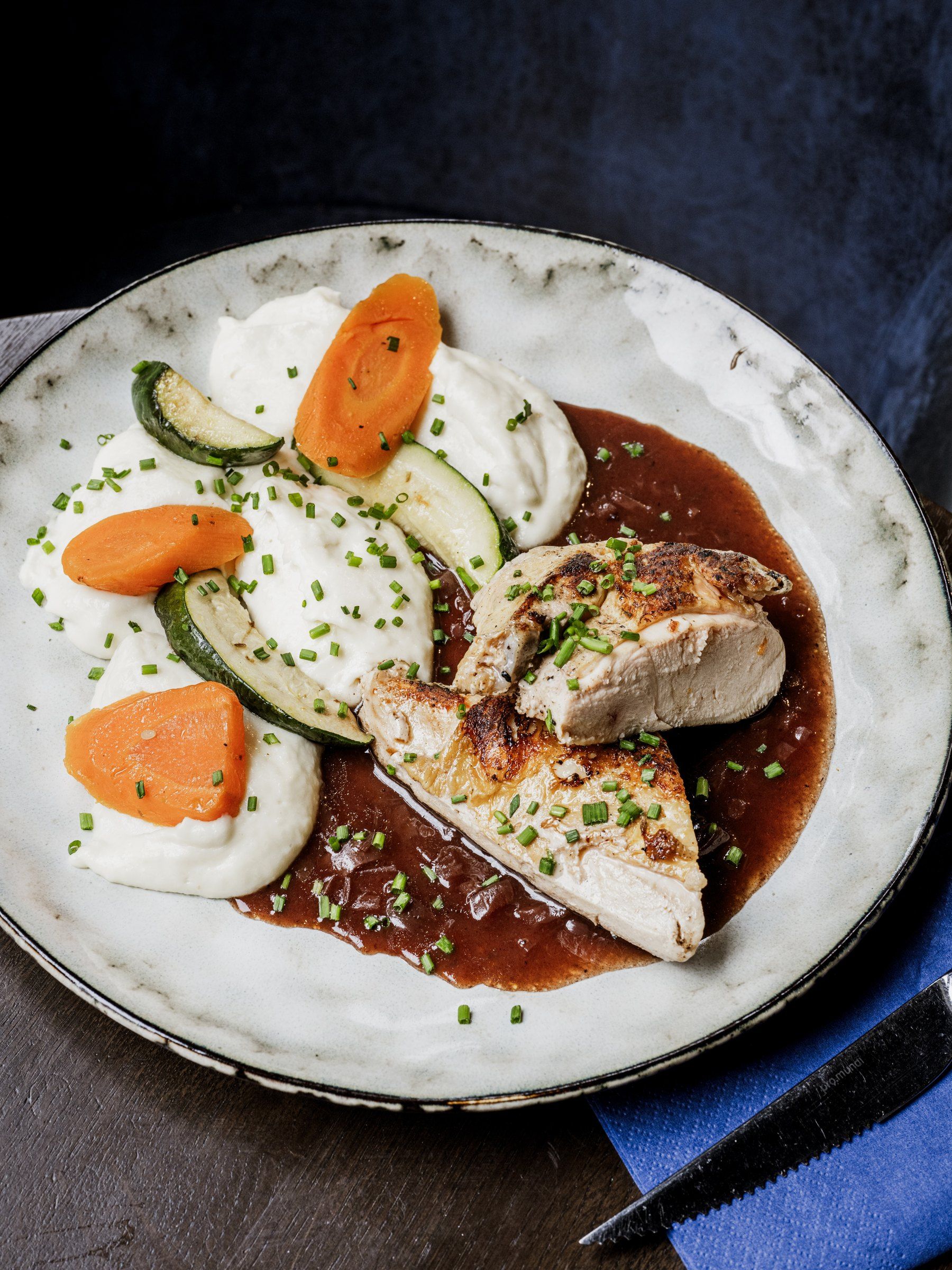 Volaille rôtie, purée, carottes et jus, dressés sur une assiette blanche